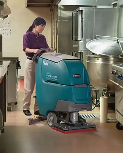 Commercial cleaning staff using walk behind scrubber provided by Thompson Flooring Solutions